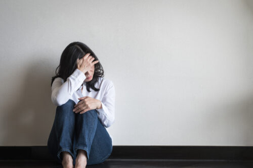 mental illness woman sitting on floor with hand covering face