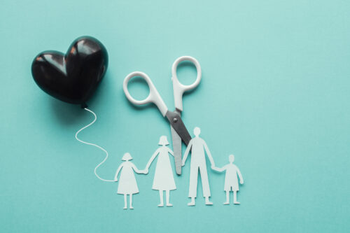 White scissor cutting family paper cut out holding black heart
