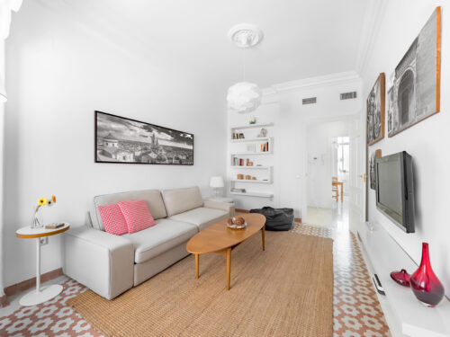 Confortable stylish bright living room with natural ratan carpet, sofa, wooden table, pictures and plants. Spacious modern interior in earthy colors