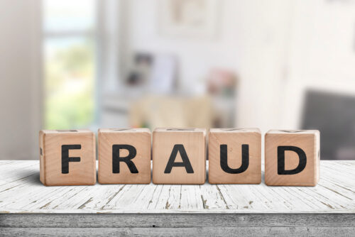 Fraud sign made of wooden blocks on a white desk